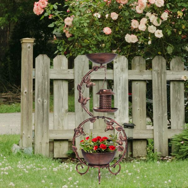Solar Powered Bird Feeder, Bath and Decorative Planter Stand In A Garden With Red Flowers
