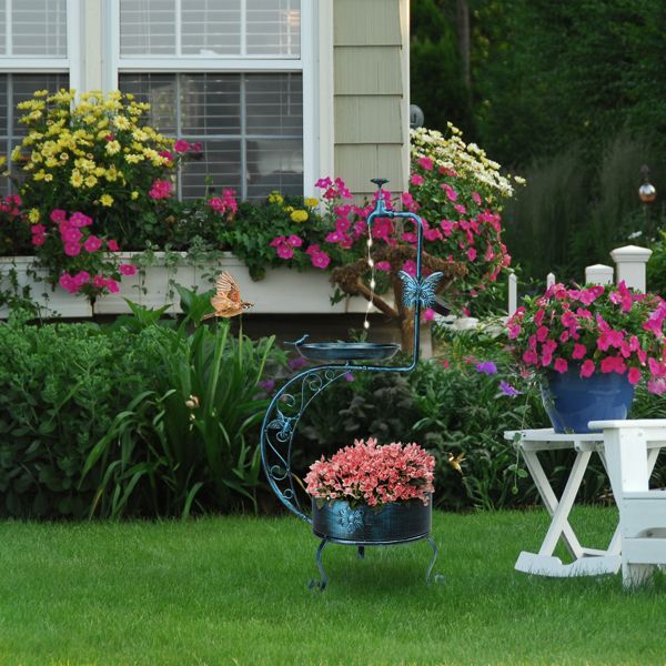 Vintage Metal Bird Bath with Solar Light and Planter In a Garden with Pink Flowers
