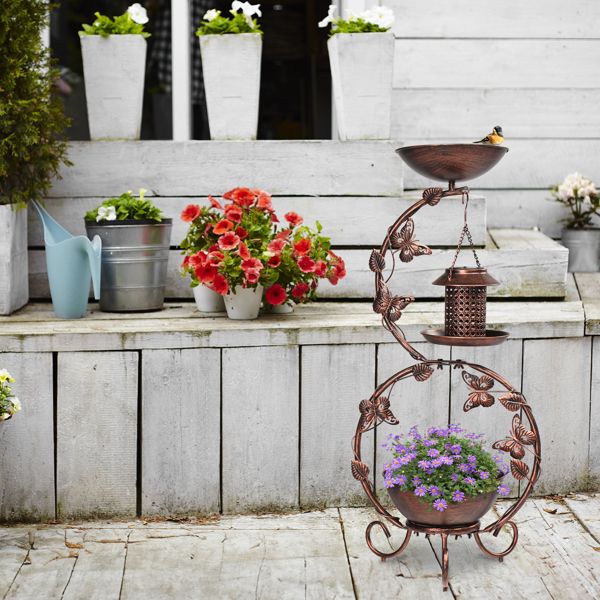 Solar Powered Bird Feeder, Bath and Decorative Planter Stand In A Garden With Purple Flowers