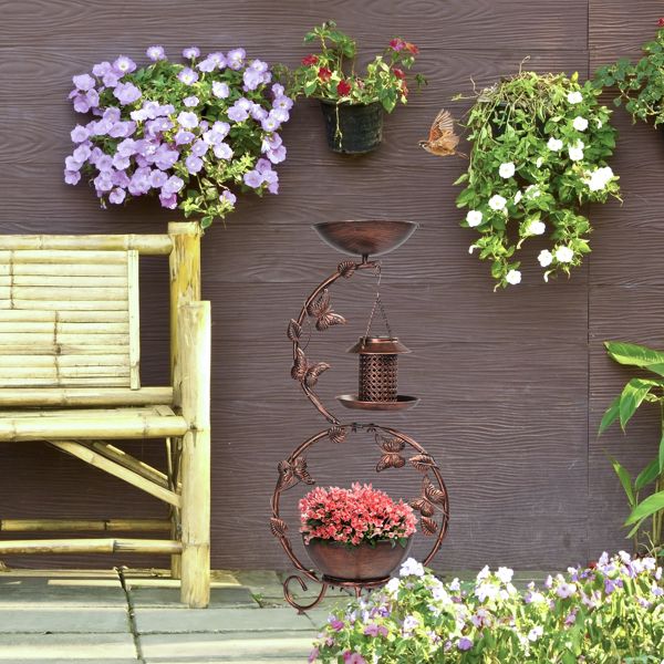 Solar Powered Bird Feeder, Bath and Decorative Planter Stand In A Garden Beside A Bench
