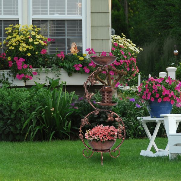Solar Powered Bird Feeder, Bath and Decorative Planter Stand In A Garden With Pink Flowers