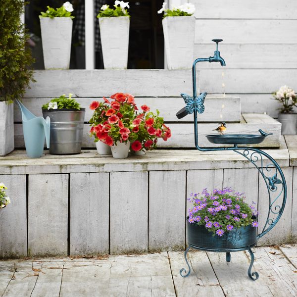Vintage Metal Bird Bath with Solar Light and Planter In A Garden With Purple Flowers